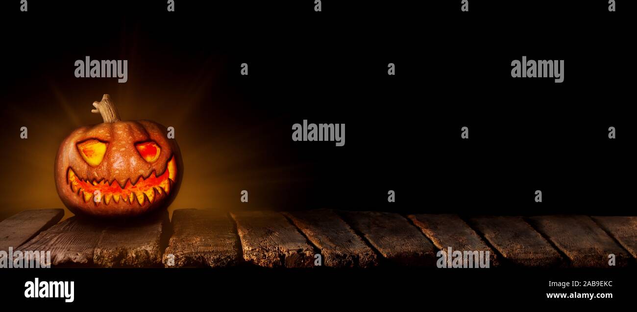 Calabaza de Halloween, Jack Oâ.Linterna brillando sobre la mesa de madera en un ambiente de miedo, embrujada. Foto de stock