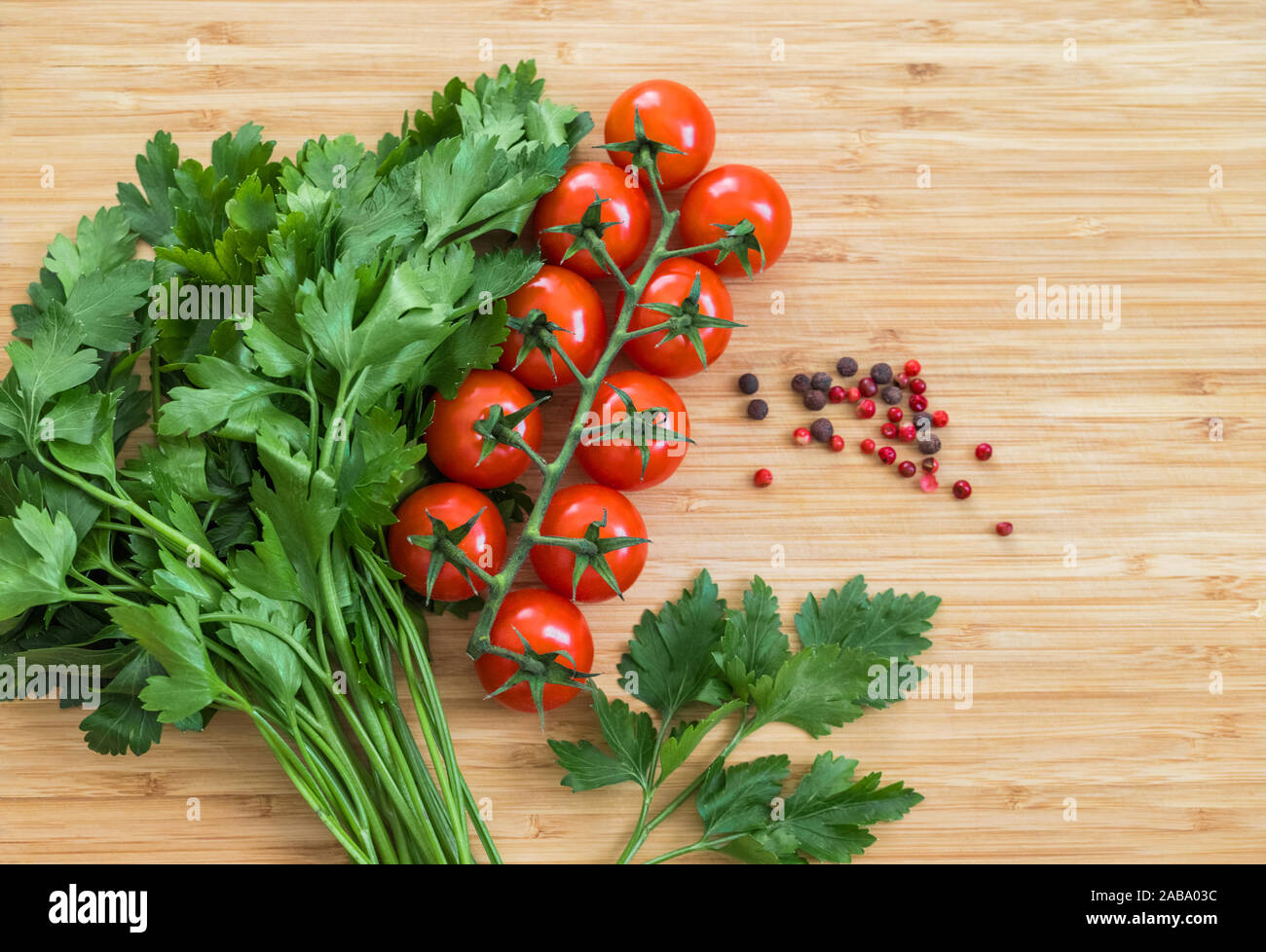 Hortalizas frescas en la mesa, espacio de copia. Fondo de alimentos. Sentar planas. Tomates Cherry, un manojo de perejil, pimientos rojos y negros sobre una plancha de madera picar Foto de stock