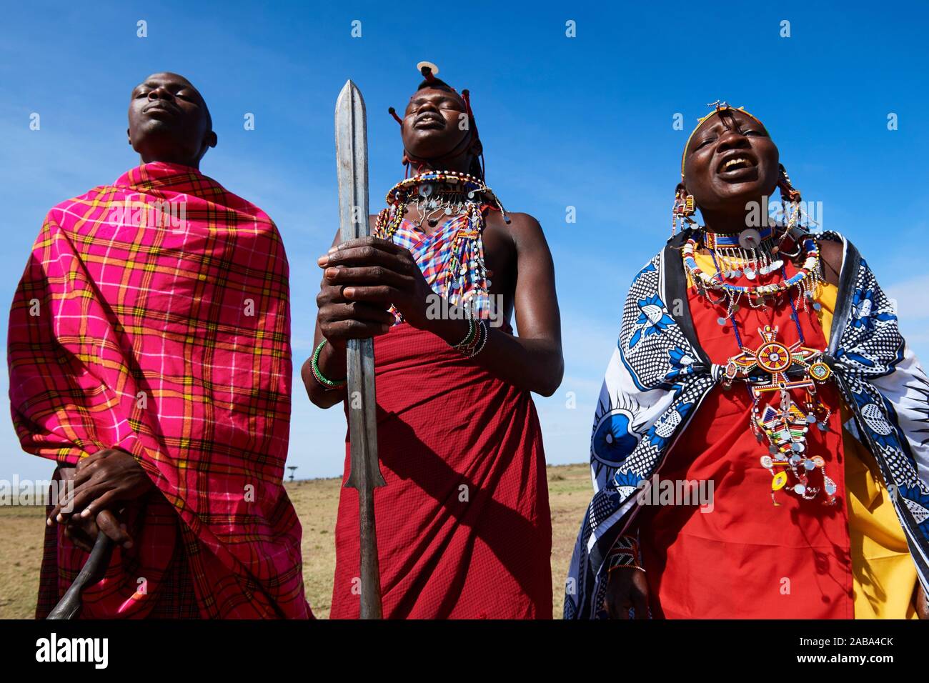Grupo de hombres y mujeres massai cantando y bailando, Reserva Nacional de Masai Mara, Kenya. Foto de stock