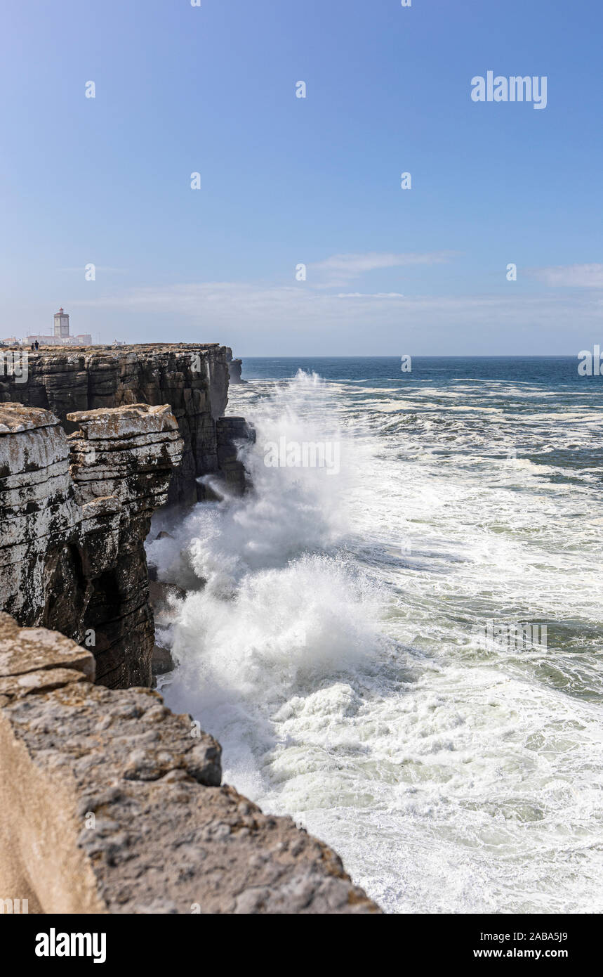 Atlántico rompiendo hinchen golpeando los acantilados en Peniche, Portugal, con el punto de Cabo Carvoeiro en la backgtound Foto de stock