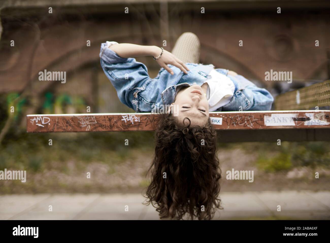 Mujer joven acostado en un banco, Berlín, Alemania. Foto de stock