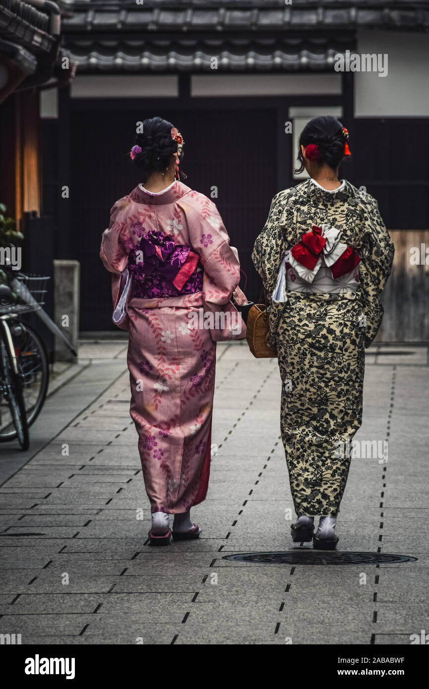 Kyoto, Japón - Octubre 2018: Dos jóvenes japoneses caminando por la calle vistiendo kimonos tradicionales. Foto de stock