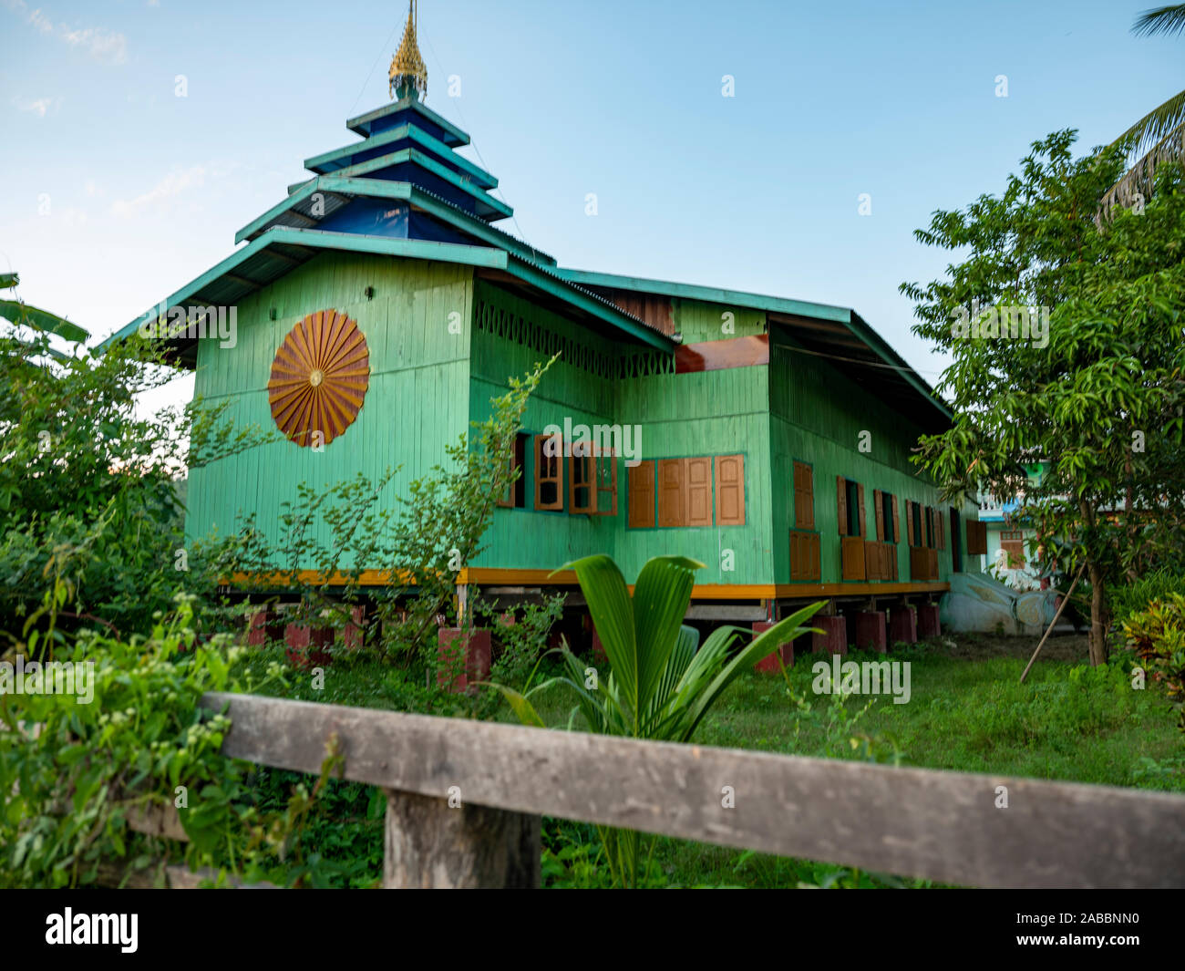 Monasterio Budista coloridas pintadas en azul y turquesa con techo de pagoda en medio de campos de arroz en la aldea de Río Chindwin KoneGyi, Myanmar (Birmania) Foto de stock