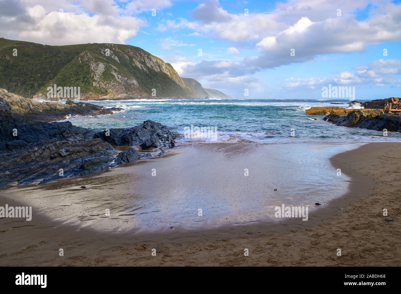 Seascape con playa de arena, el azul del océano y las montañas verdes, el Parque Nacional de Tsitsikamma, Garden Route, Eastern Cape, Sudáfrica Foto de stock