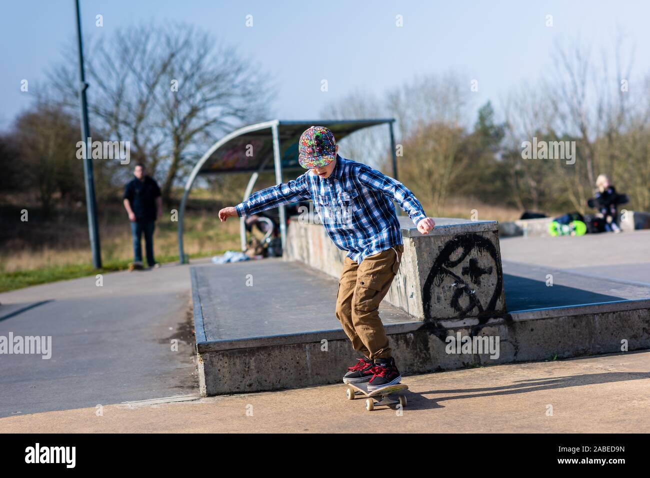 Un pequeño y lindo niño con síndrome de Asperger, autismo, ADHD caballo alrededor del skatepark escuchando música y practicar trucos, baje las escaleras, Ollie etc Foto de stock