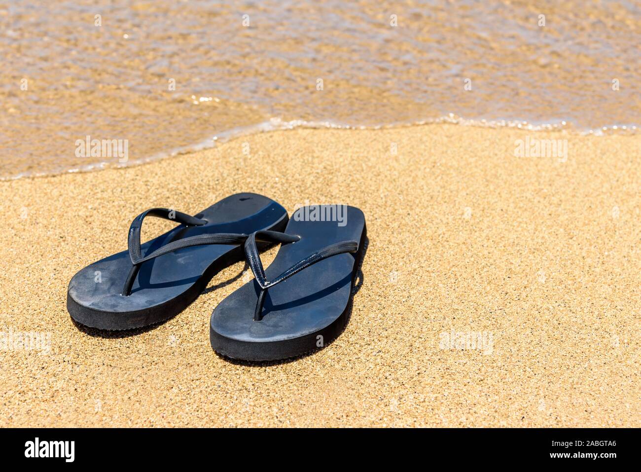 Un par de sandalias (chanclas), en una costa hawaiana, con el mar bañando  cerca de los zapatos Fotografía de stock - Alamy