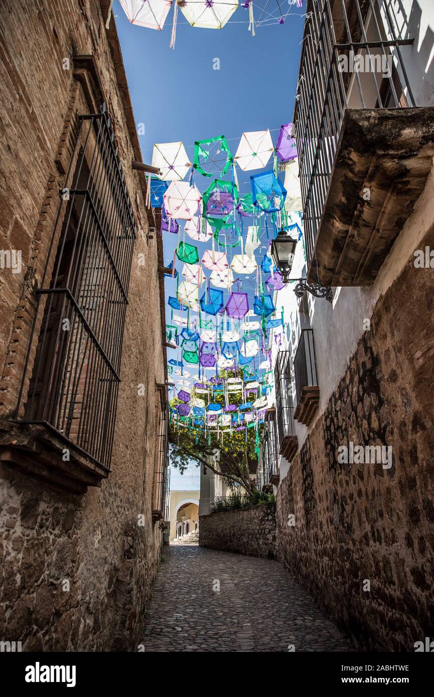 Callejon del Beso en Alamos, Sonora, México. apedreado ruta con decoración  tradicional de las fiestas populares de los pueblos con exagonos de colores  azul y violeta de papel colgando de hilos. banderines
