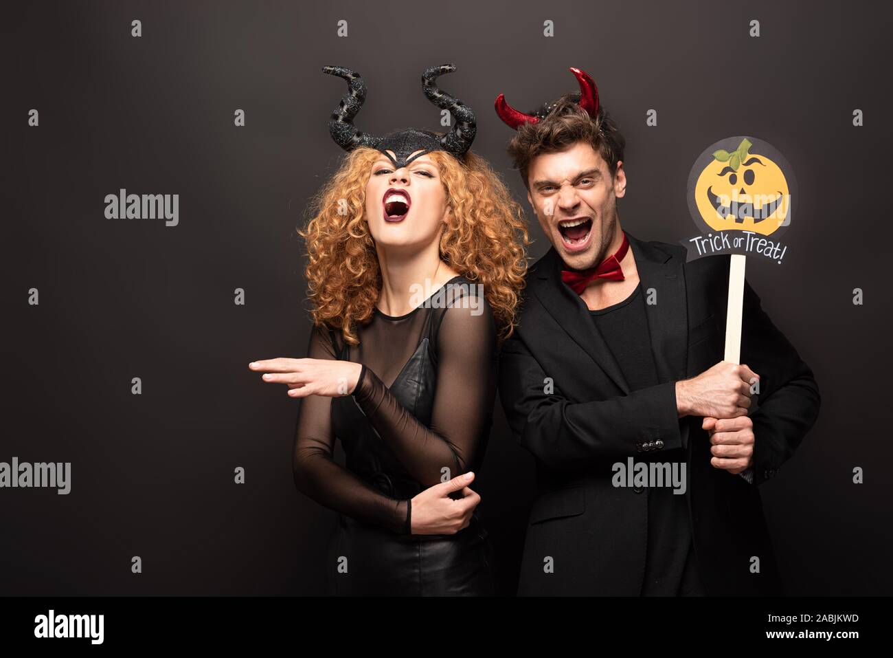 Pareja de miedo posando en disfraces de Halloween con calabaza trick or  treat firmar sobre negro Fotografía de stock - Alamy