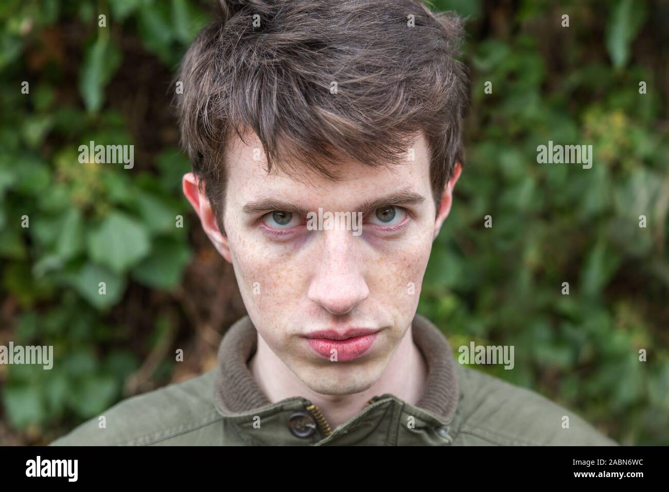 Un hombre joven en su adolescencia o principios del veinte miradas amenazadoras como él mira hacia la cámara con una mirada intimidante. Foto de stock