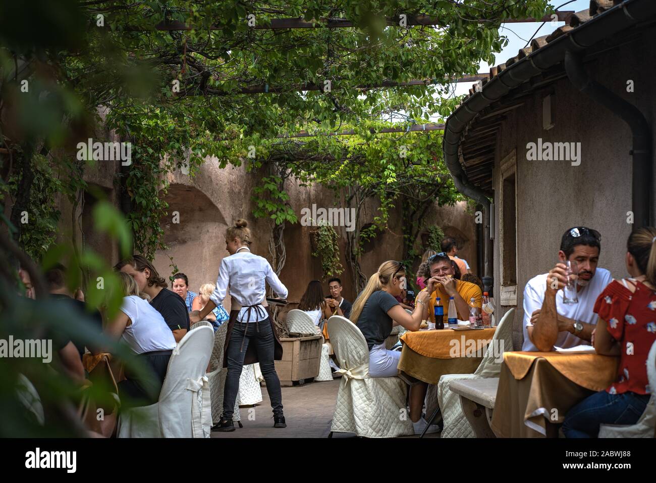 Los turistas en el bar en el interior del castillo de Sant'Angelo. Hermosa foto de gente disfrutando en el bar italiano. El camarero está sirviendo. Foto de stock