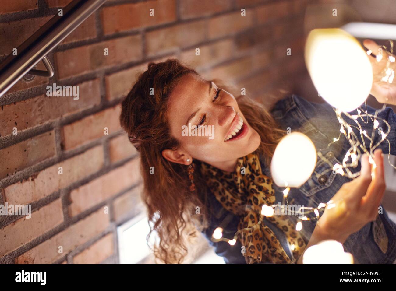 20s alegre pelirroja mujer caucásica jugando con las luces de hadas afuera Foto de stock