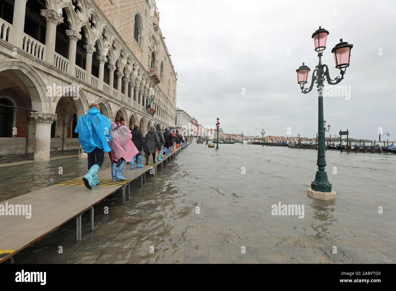 Muchas personas en pasarela con plástico polainas en Venecia en Italia durante el impresionante récord de inundaciones Fotografía de stock - Alamy