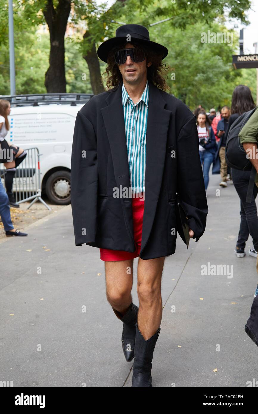 Milán, Italia - 19 de septiembre de 2019: el hombre chaqueta negra y botas de vaquero caminando antes de Fendi Fashion Show, la Semana de la moda de Milán street style