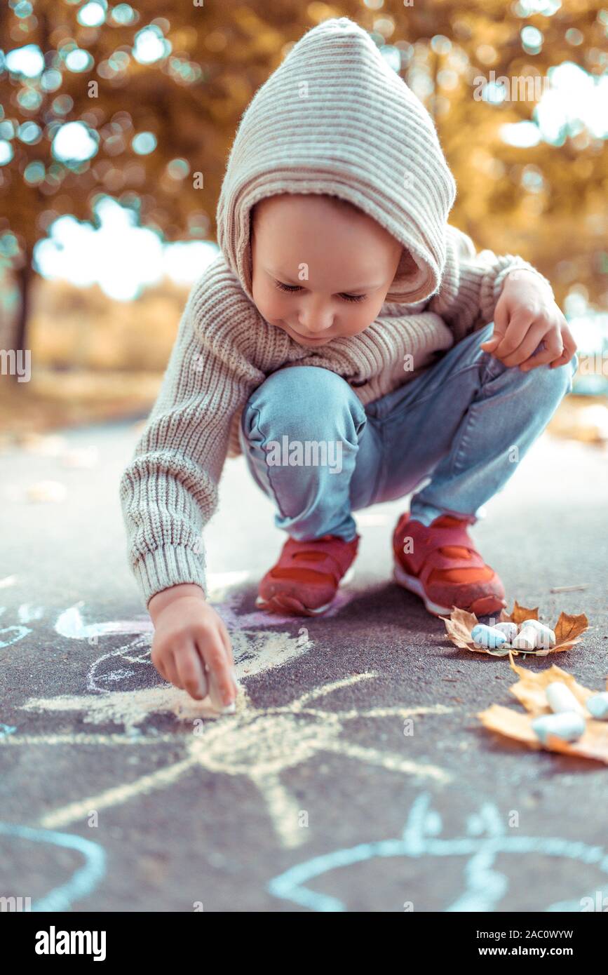 Niño 3-6 años, en otoño, en la calle, atrae sobre pavimento, lápices de colores. caliente en un día frío, beige chaqueta con capucha. Fin semana Fotografía de stock - Alamy