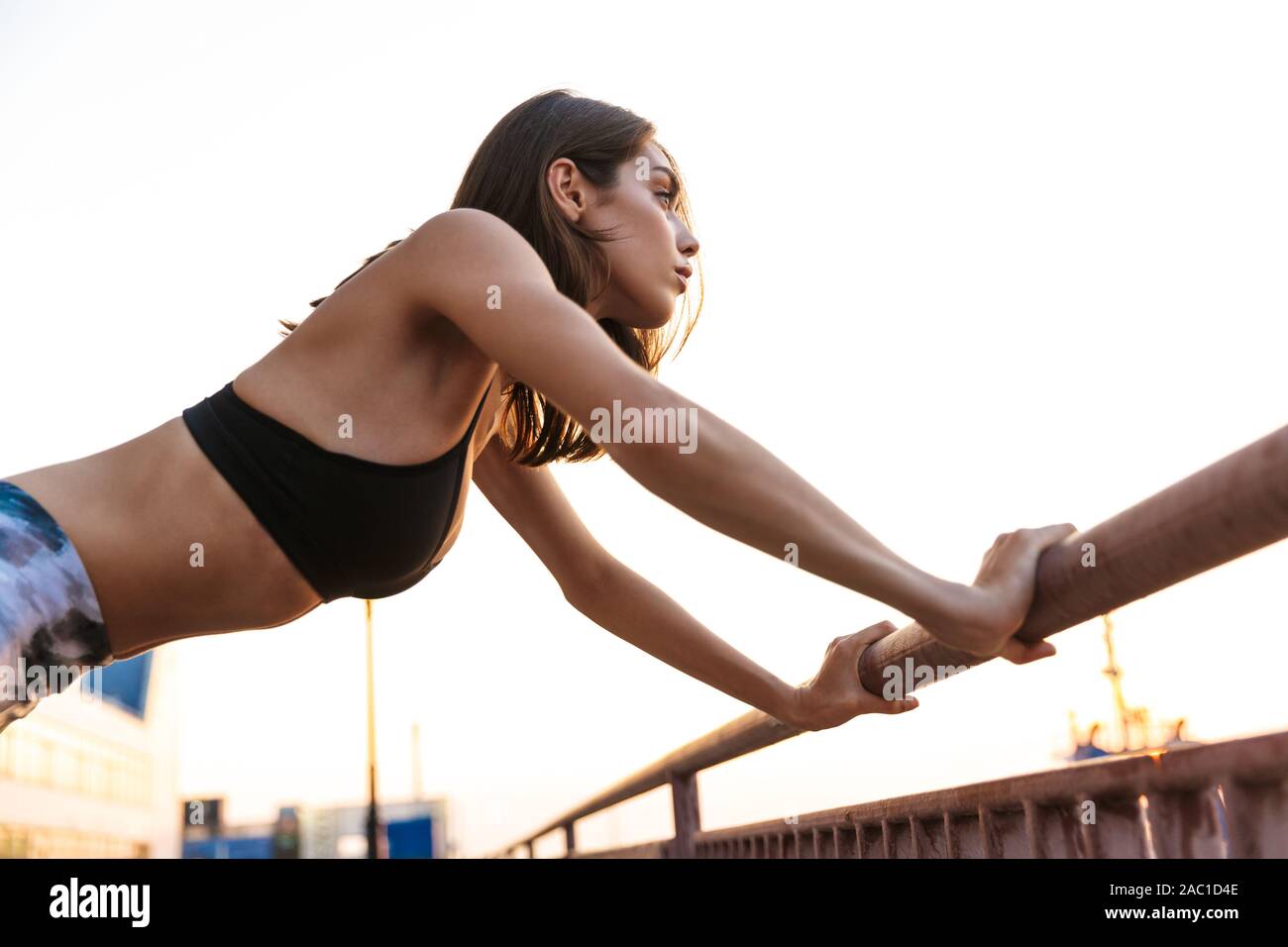 Imagen de joven mujer deportiva en ropa deportiva haciendo ejercicio con  baranda mientras trabajaba en el puerto marítimo de mañana Fotografía de  stock - Alamy