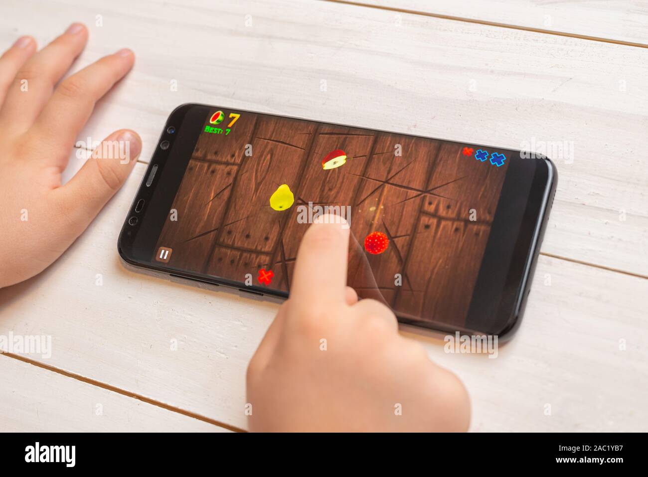 Sarajevo, Bosnia y Herzegovina - Noviembre 30, 2019: Kid jugando Fruit Ninja juego de video en el teléfono inteligente moderno cerrar Foto de stock