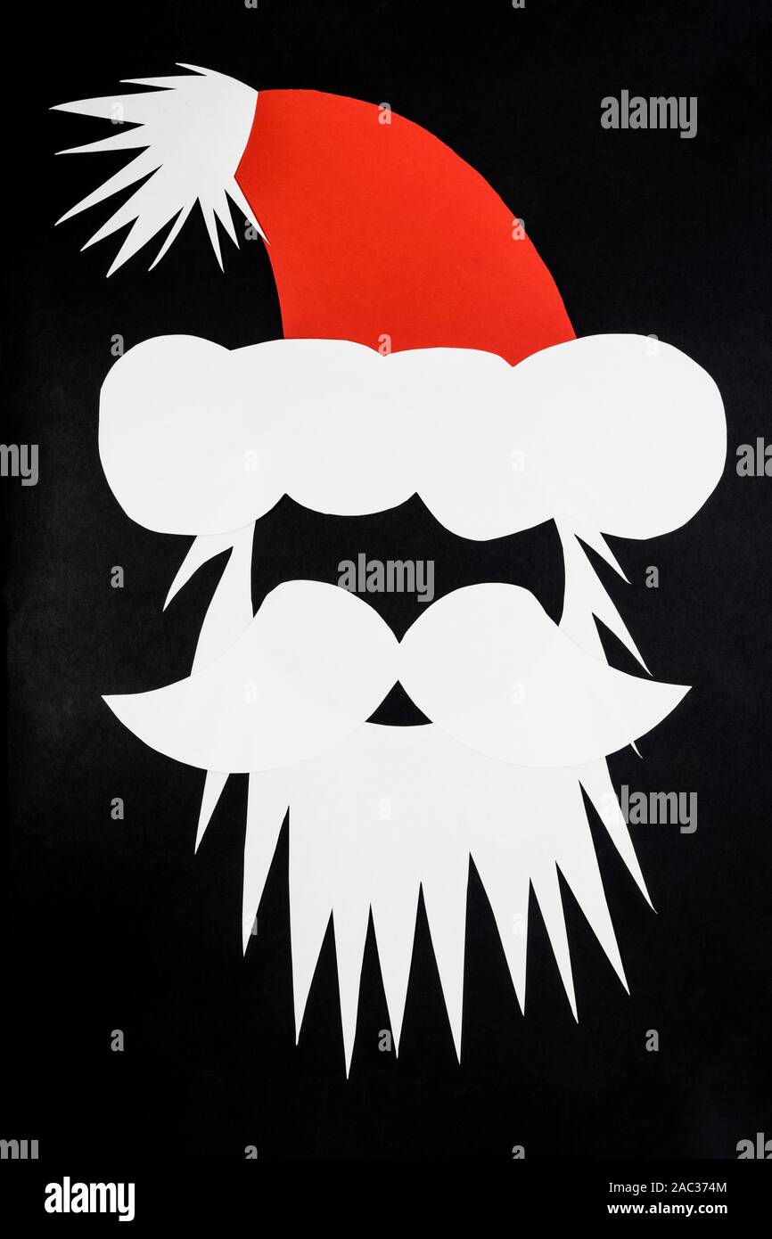 Composición abstracta de Santa Claus cabeza con gorra blanca de nd papel rojo y se coloca sobre fondo negro y gris oscuro con espacio de copia Foto de stock