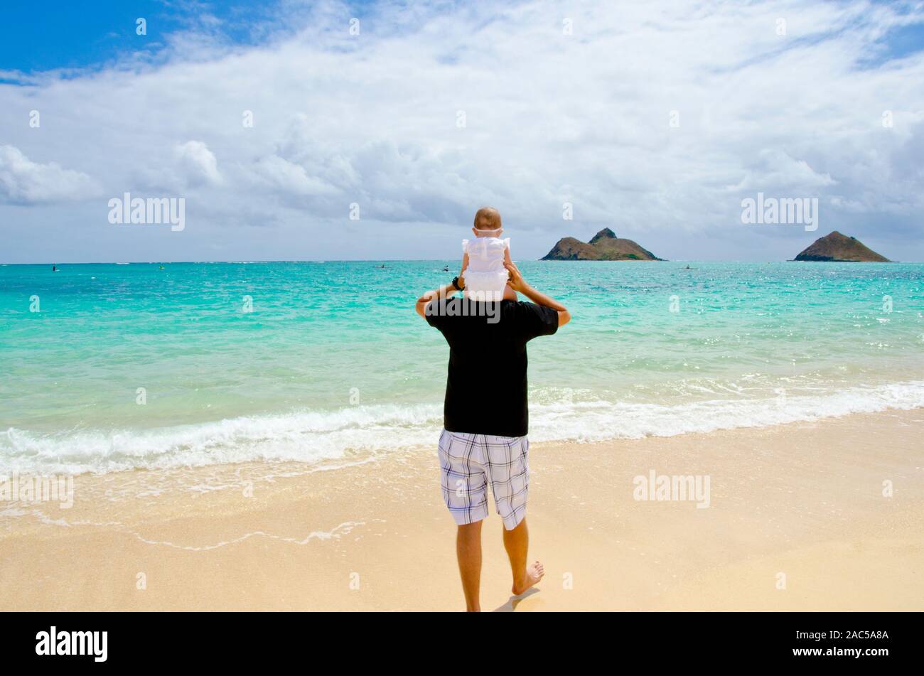 Papá Jason con el bebé Emma sobre sus hombros en Lanikai beach, Kailua, Oahu Foto de stock