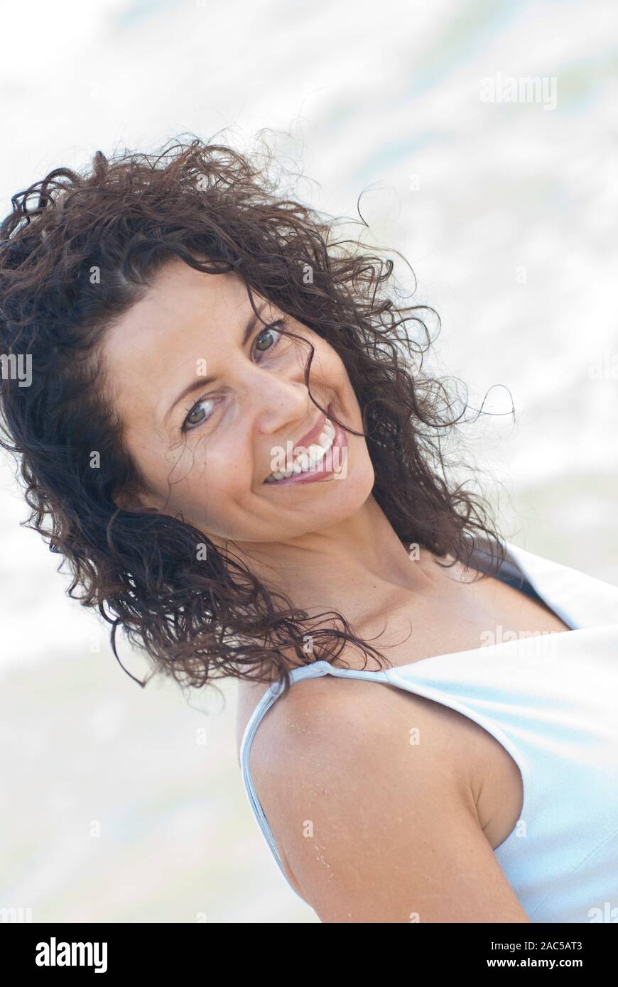 Retrato tomado en la playa de Kailua hermosa mujer de pelo rizado a la edad de 50 años vistiendo vestido azul suave Foto de stock