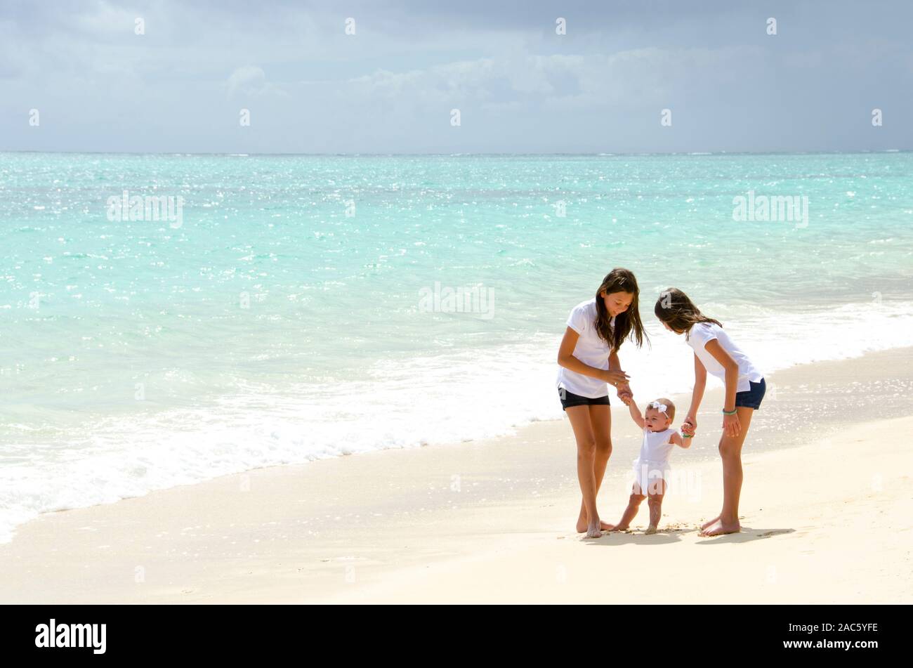 Hermanas Leilani y ke'alohi cuidando de su bebé en la playa hermana Emma Foto de stock
