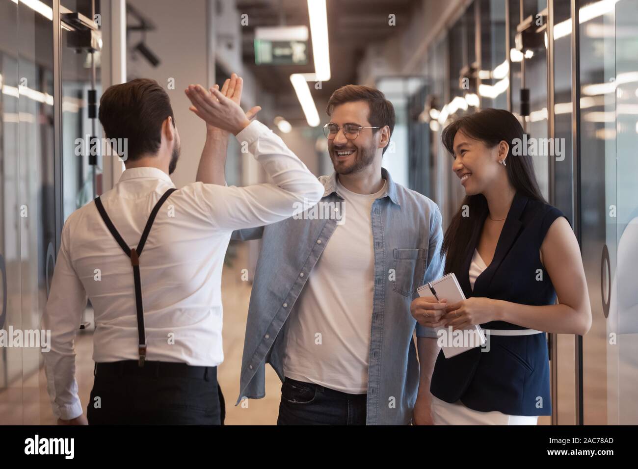 Los empleados de pie en el pasillo saludándonos dando alta cinco Foto de stock