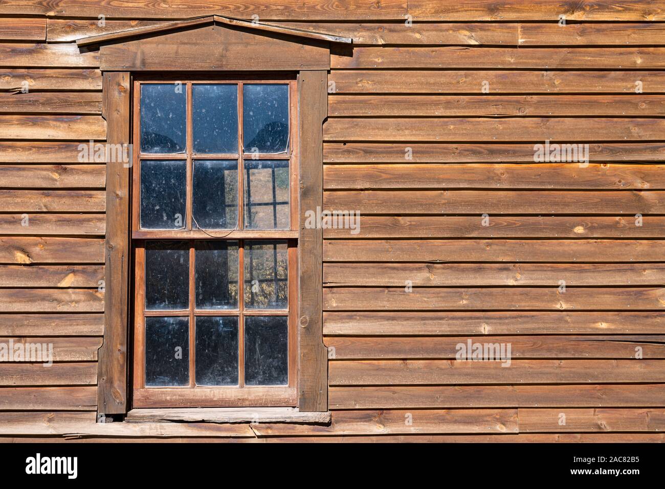 En la ventana de un edificio antiguo de madera desgastada Foto de stock