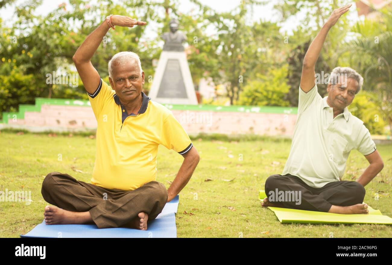 Feliz altos gente haciendo yoga por estiramiento manos - Concepto de personas mayores fitness y estilo de vida saludable - dos ancianos hombre ocupado en ejercicio matinal Foto de stock