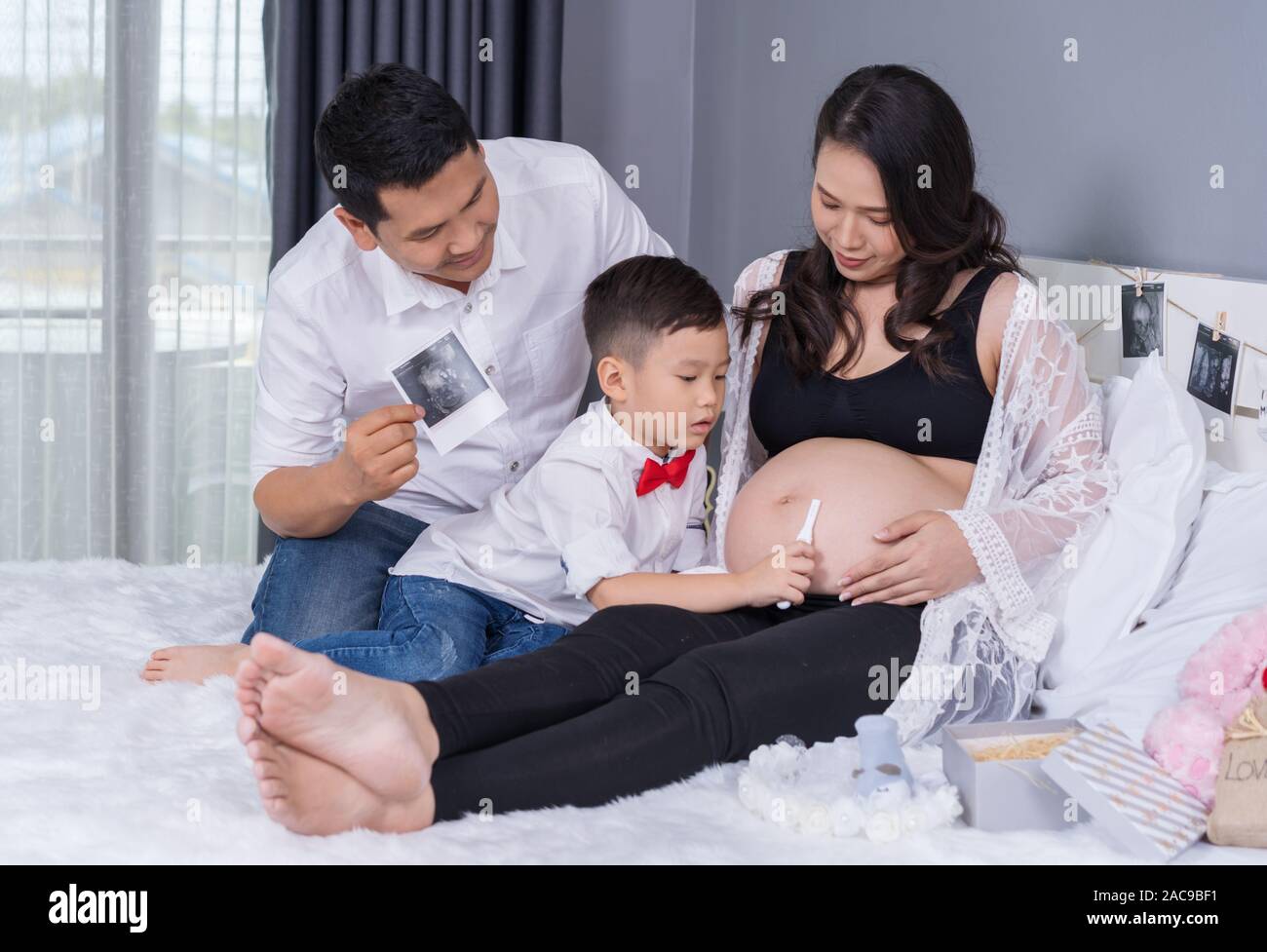 Concepto de familia feliz, la madre embarazada, padre e hijo, con prueba de  embarazo en la cama Fotografía de stock - Alamy