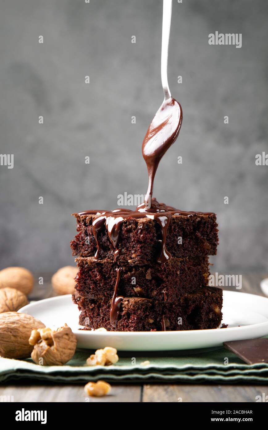 Pasteles brownie esponjoso de chocolate con nueces y una cuchara verter el  chocolate derretido topping Fotografía de stock - Alamy