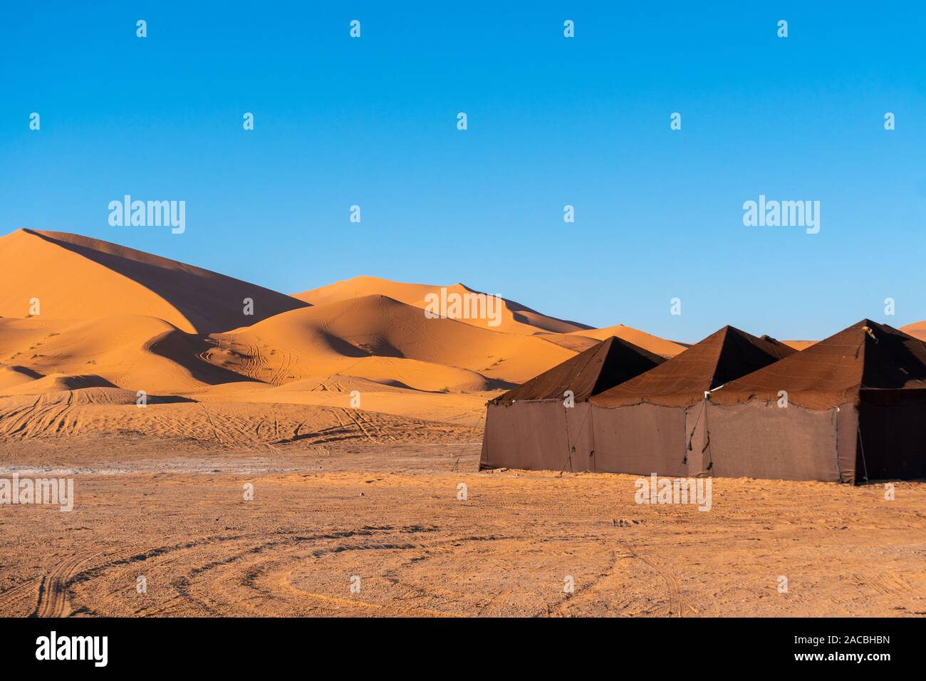 Luxury brown Tent Camp en el desierto de Sahara Merzouga, Marruecos en un día soleado, con dunas de arena en el fondo Foto de stock
