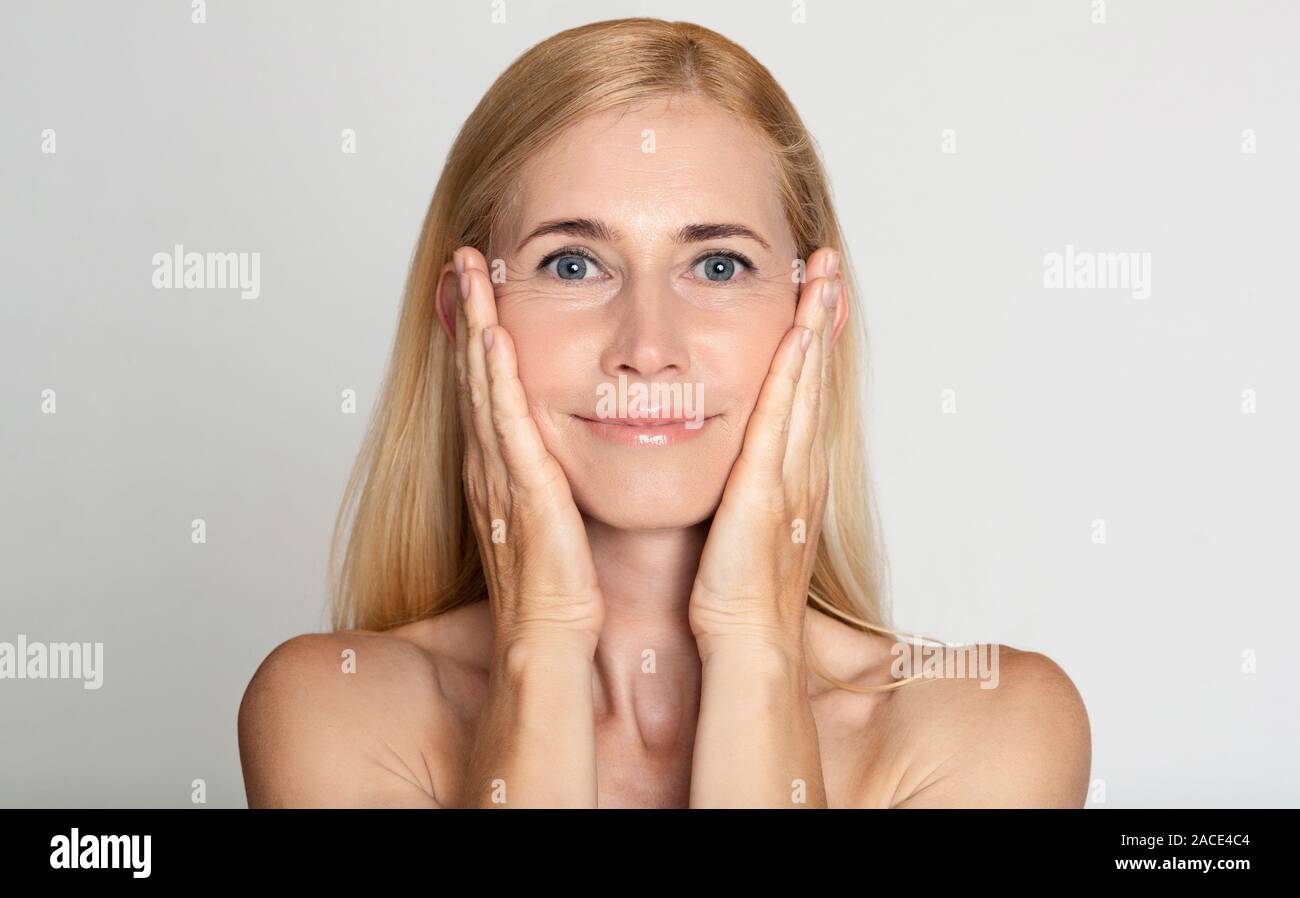 Tratamiento antiedad. Mujer de mediana edad tocar las mejillas Foto de stock