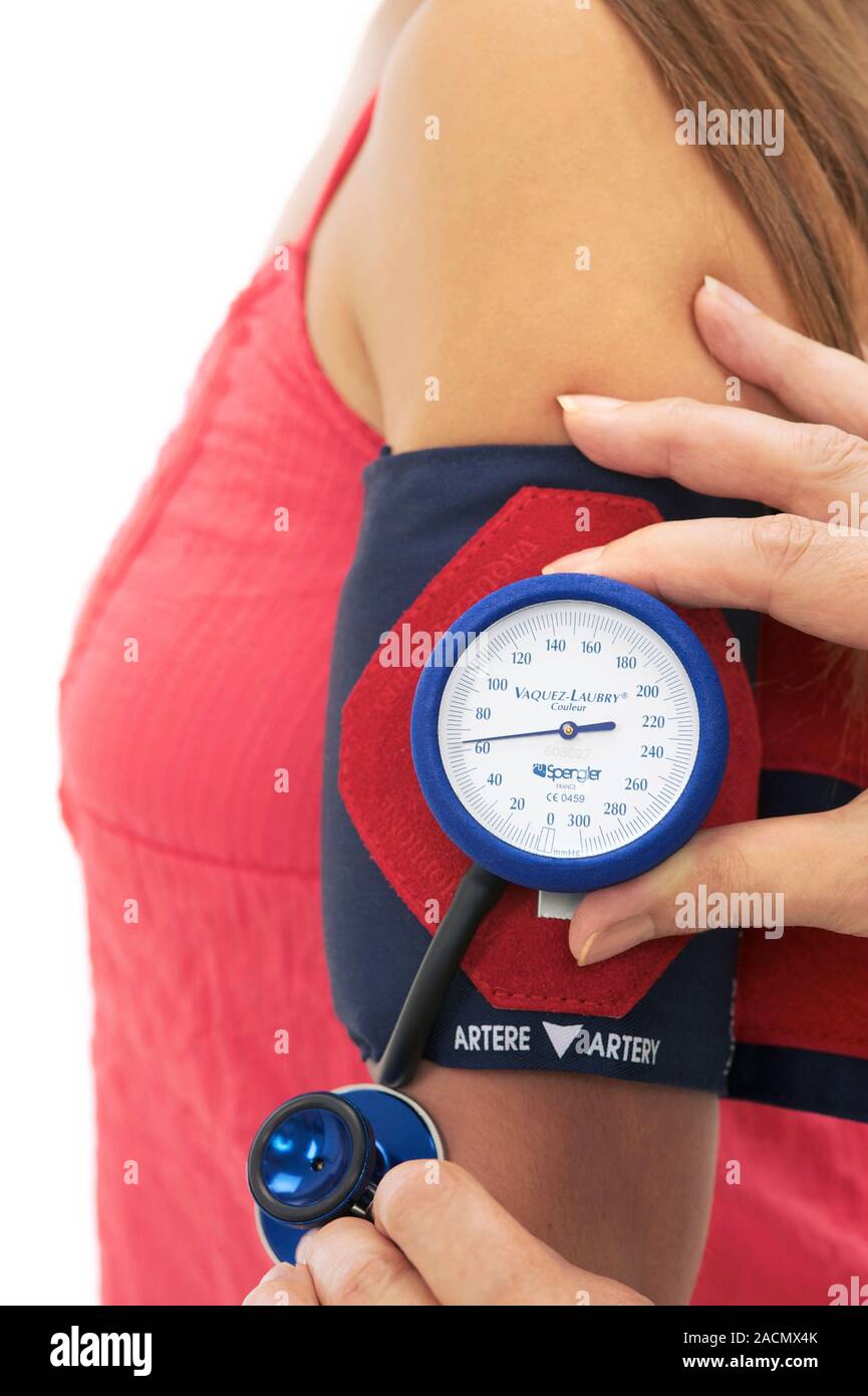 Lectura de la presión arterial en una mujer con un esfigmomanómetro. Un  manguito inflable ha sido colocada alrededor de la parte superior del brazo  y se infla hasta que corta Fotografía de