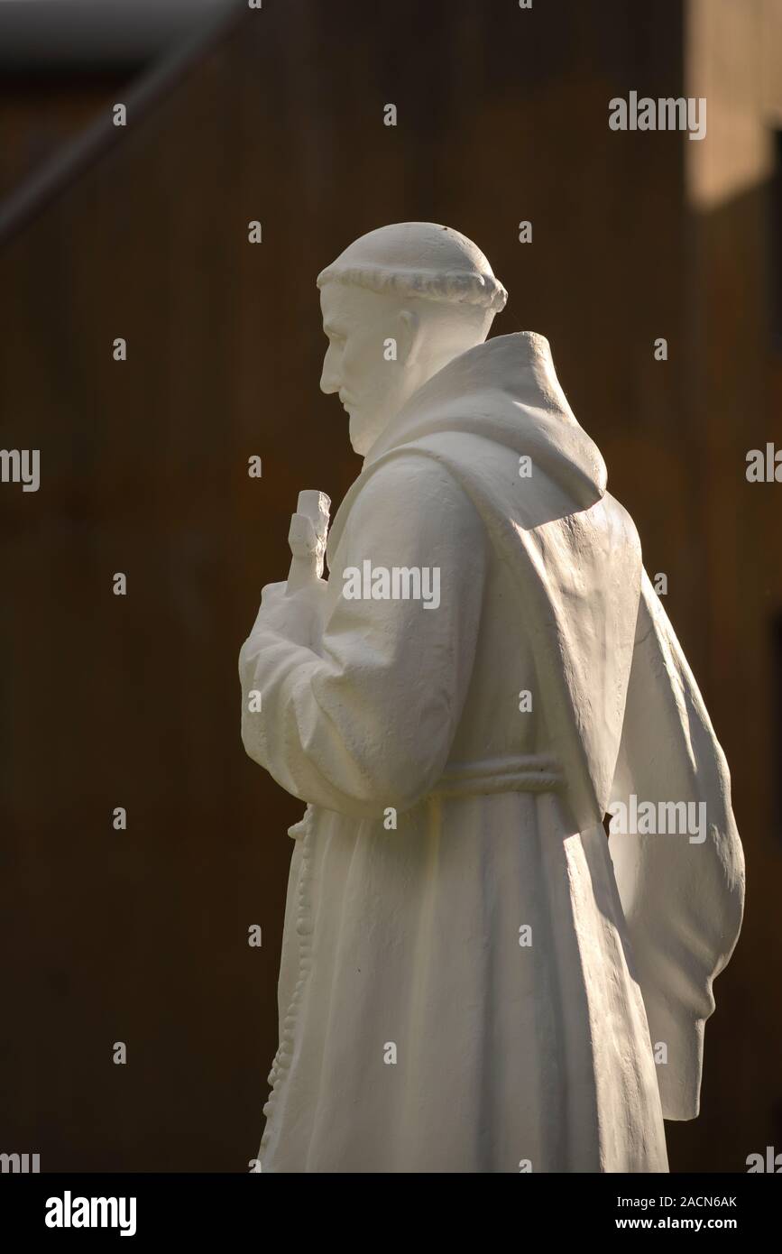 Figura religiosa estatua de un monje franciscano vistiendo hábito túnica y  sosteniendo una santa cruz en una luz espectacular. Efecto del claroscuro  Fotografía de stock - Alamy
