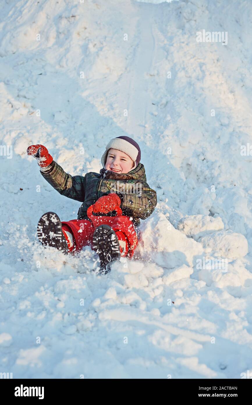 Niño sobre un trineo de plástico bajando una colina de nieve Fotografía de  stock - Alamy
