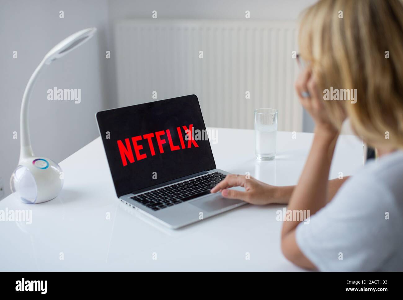 Mujer joven con portátil con Netflix en la pantalla seeting logo en el  escritorio de la oficina. Una chica en la oficina viendo Netflix Fotografía  de stock - Alamy