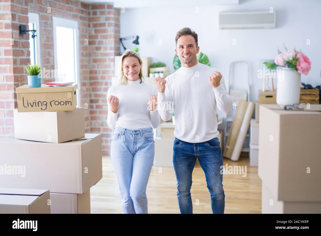Hermosa joven pareja de pie en la nueva casa alrededor de cajas de ...