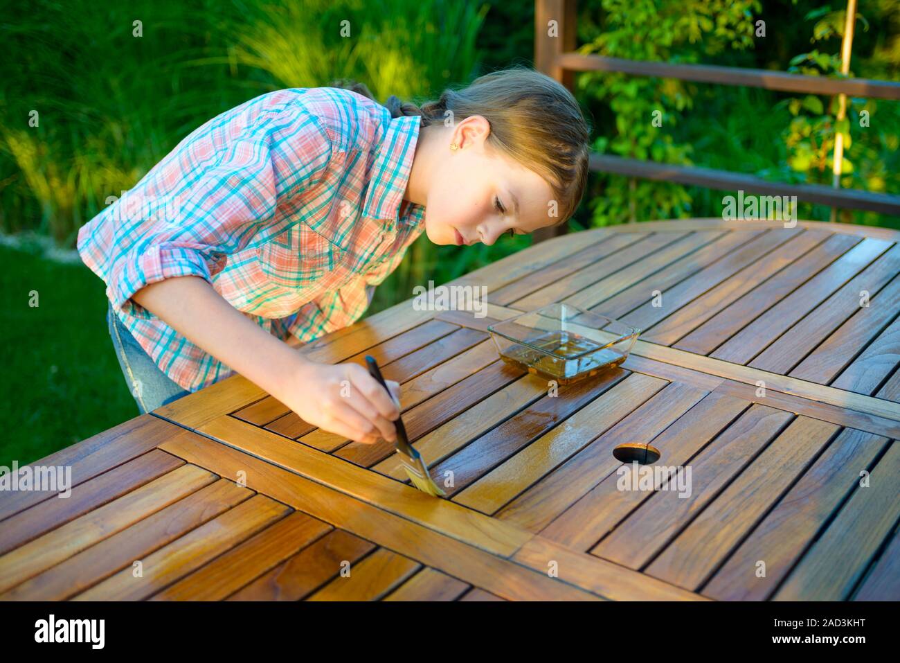 Chica guapa joven sosteniendo un pincel aplicar pintura barniz sobre una  mesa de jardín de madera Fotografía de stock - Alamy