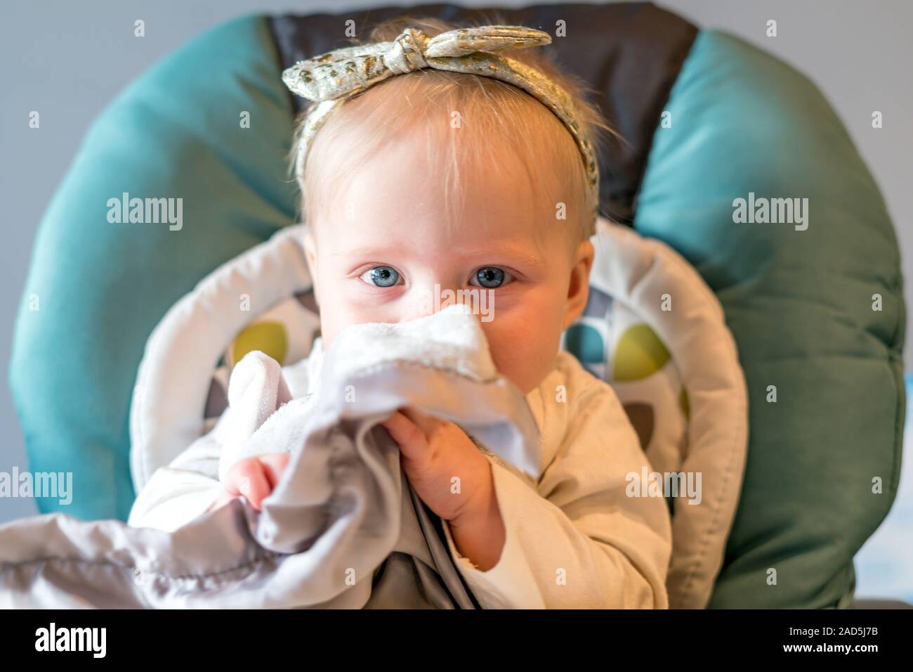 Niña con ojos azules en la silla alta - edad 6 meses Foto de stock