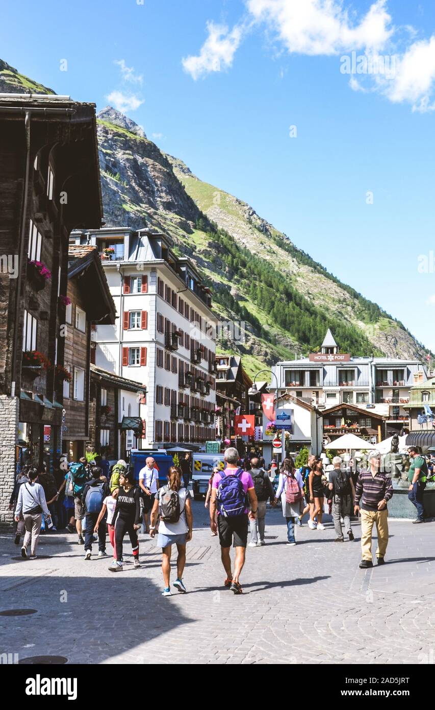 Zermatt, Suiza - 10 de julio de 2019: Calle con turistas en la bella aldea alpina Zermatt en la temporada de verano. El centro de la ciudad con la gente. Alpes Suizos. Destinos de viaje. Foto de stock