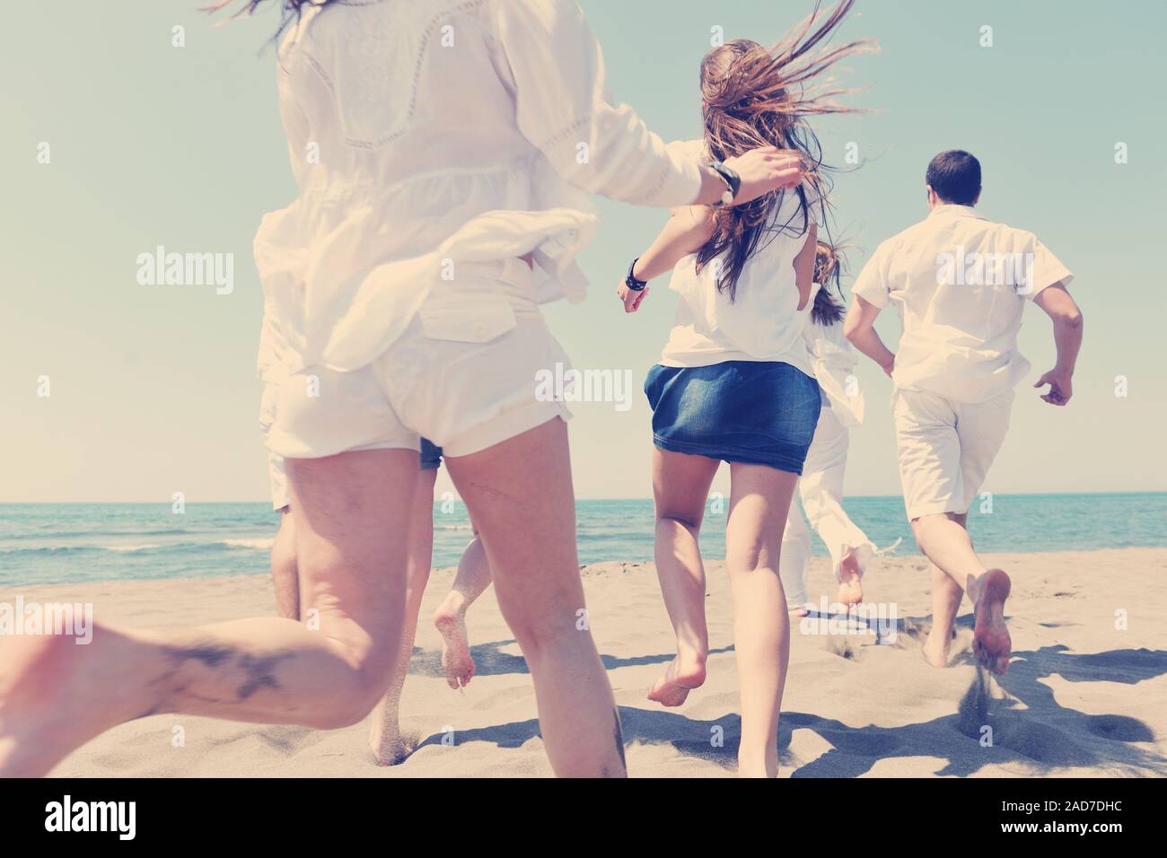 Grupo de personas felices, divertirse y corriendo en la playa Foto de stock