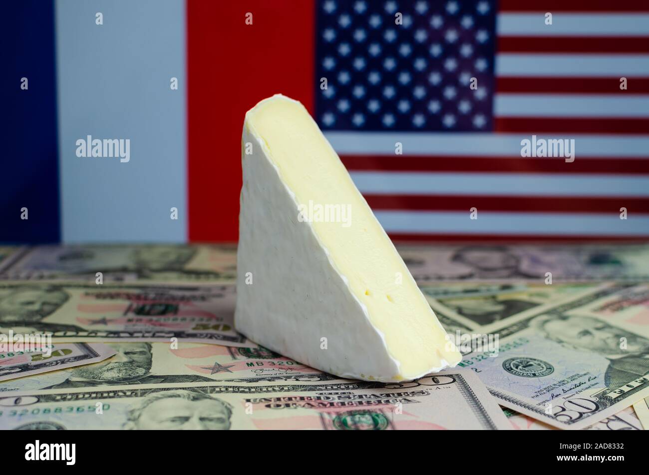 Queso francés Brie encima de nosotros los billetes en dólares y las banderas de los Estados Unidos y Francia en segundo plano. Para nosotros Conceptual y Francia guerra comercial. Foto de stock