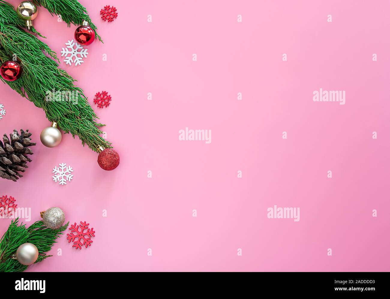 Pino Verde , piña , los copos de nieve , adornos navideños bola roja sobre fondo de color rosa con espacio de copia Foto de stock