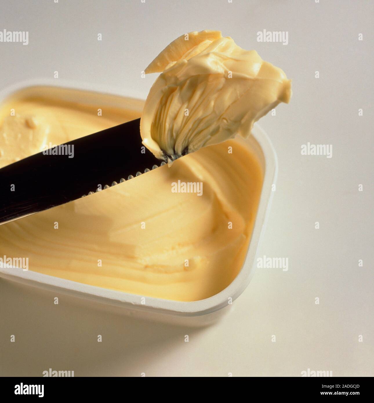 La margarina. Bocas de cuchilla margarina desde un envase de plástico. La  margarina es un sustituto de la mantequilla que no contenga grasa láctea,  pero generalmente se hace desde hort Fotografía de