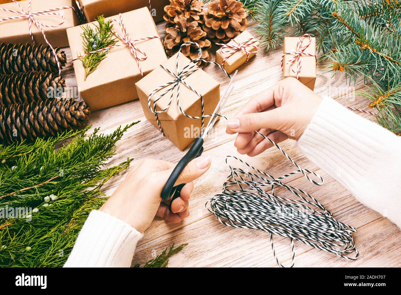 Regalos hechos a mano sobre fondo de madera con decoración de Navidad.  Mujer envolver regalo de navidad , Niña prepara regalos navideños con cono  de pino y abeto Fotografía de stock - Alamy
