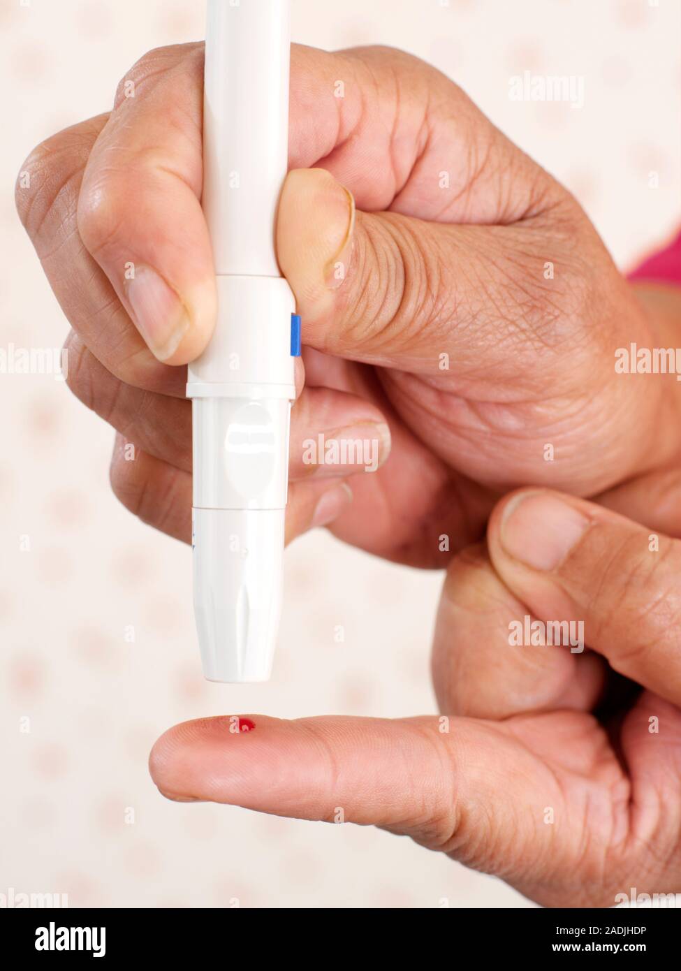 Modelo liberado. Prueba de glucosa en la sangre. Close-up de una mujer con  un lápiz como dispositivo lancing para pincharse el dedo antes de una  prueba de glucosa en la sangre. Los