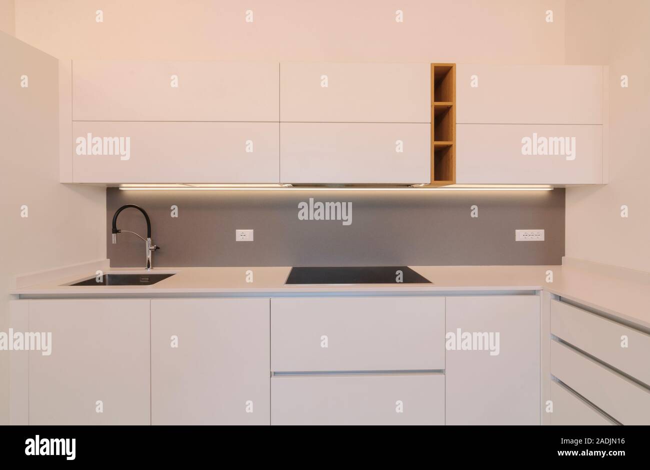 Cocina moderna y elegante interior con alacenas blancas, placa de inducción  y inserciones de madera. Estilo escandinavo contemporáneo Fotografía de  stock - Alamy