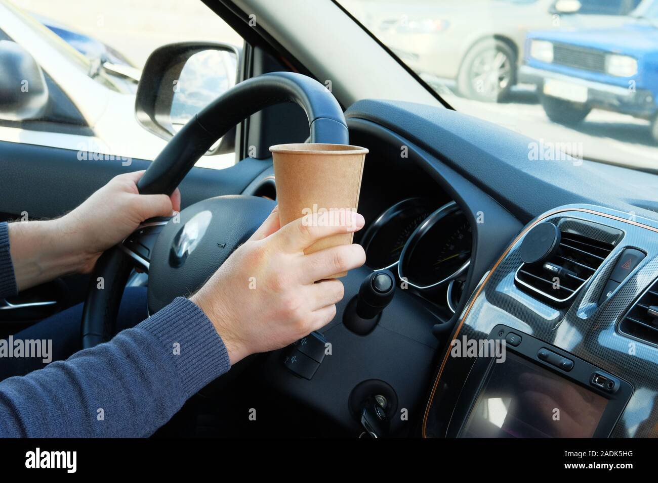 Vaso de papel con té o café en la mano del controlador en coche en sunny  fondo difuminado. Comida para llevar, los medios de comunicación social. El  desayuno por la mañana en