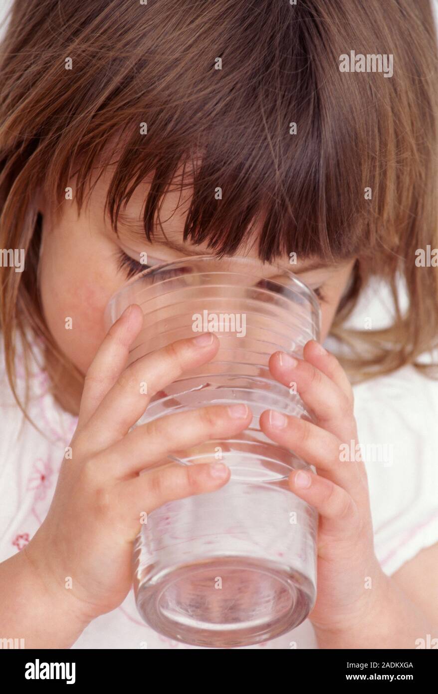 Niña de agua potable. Niña de 3 años de beber agua de un vaso. El agua es  esencial para la buena salud, ya que reduce la cantidad de grasa que se  depositan