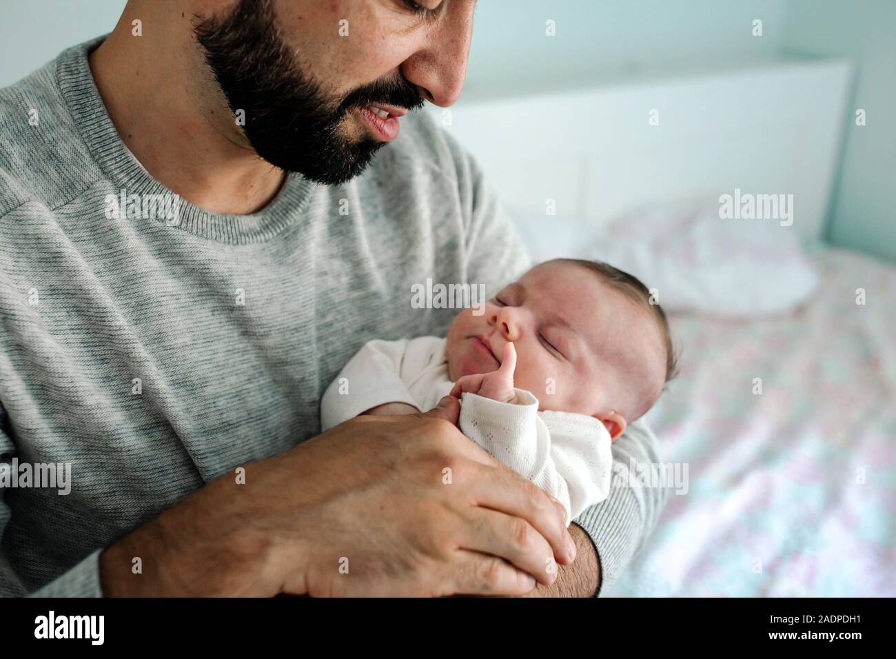 Papá barbudo mantiene amorosamente recién nacido con discapacidad cotidiana Foto de stock