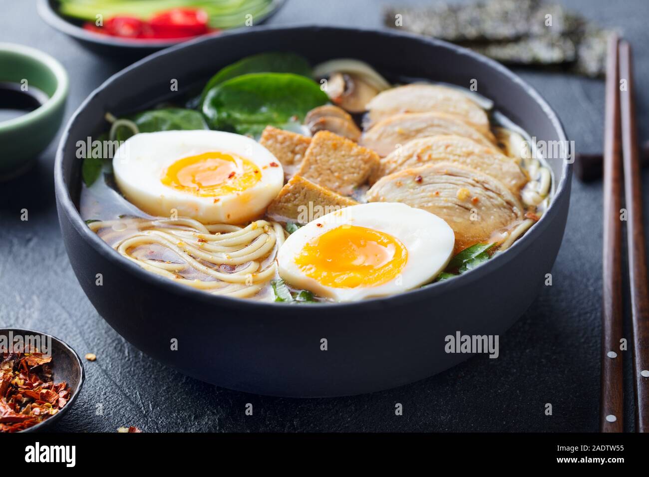 Asia, sopa de fideos ramen con pollo, tofu, verduras y huevo en el tazón  negro. Fondo de pizarra. Cerrar Fotografía de stock - Alamy